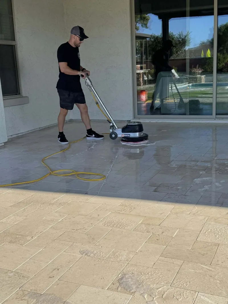 Rotary scrubber deep cleaning a covered travertine patio before sealing