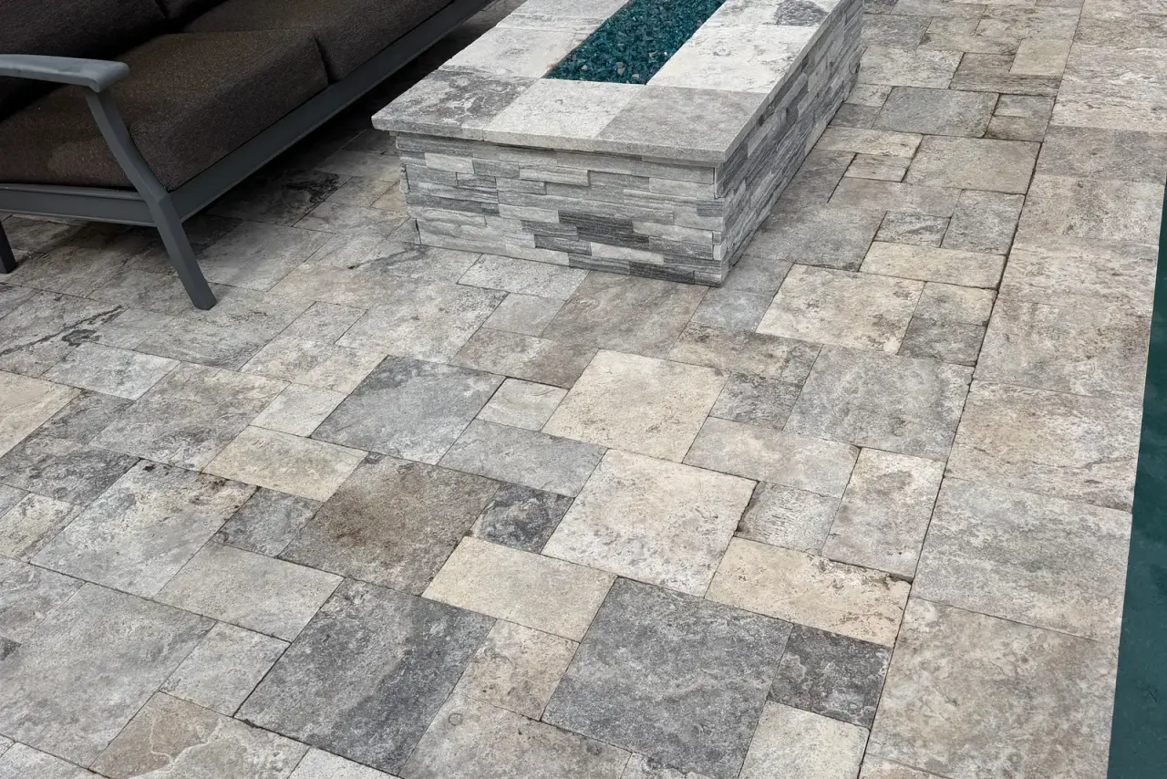 Bright clean travertine patio along a stucco wall after pressure washing