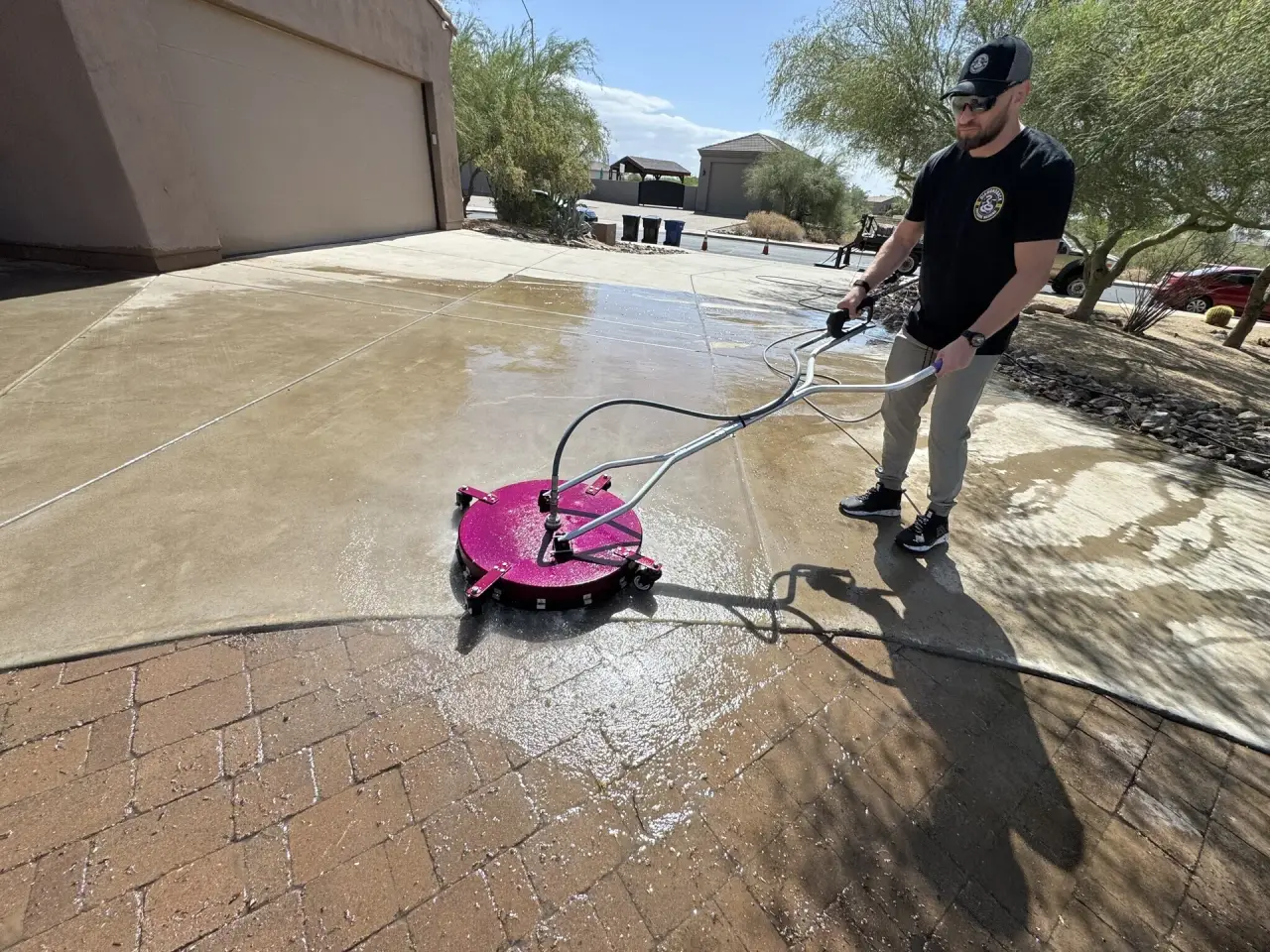 Diamondback tech surface-cleaning a Gilbert concrete driveway, clean vs dirty split visible