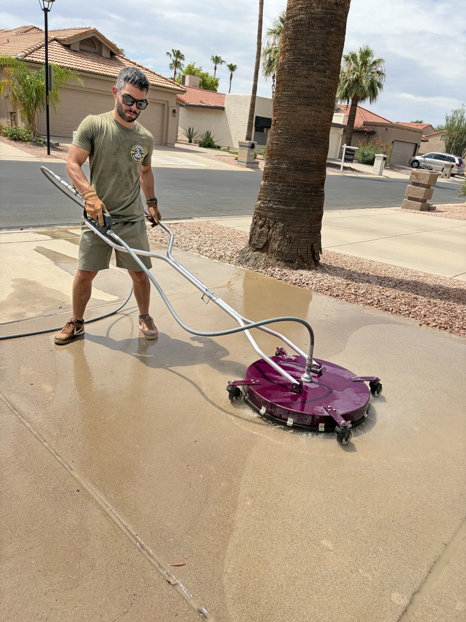 Diamondback technician cleaning a concrete driveway with a surface cleaner