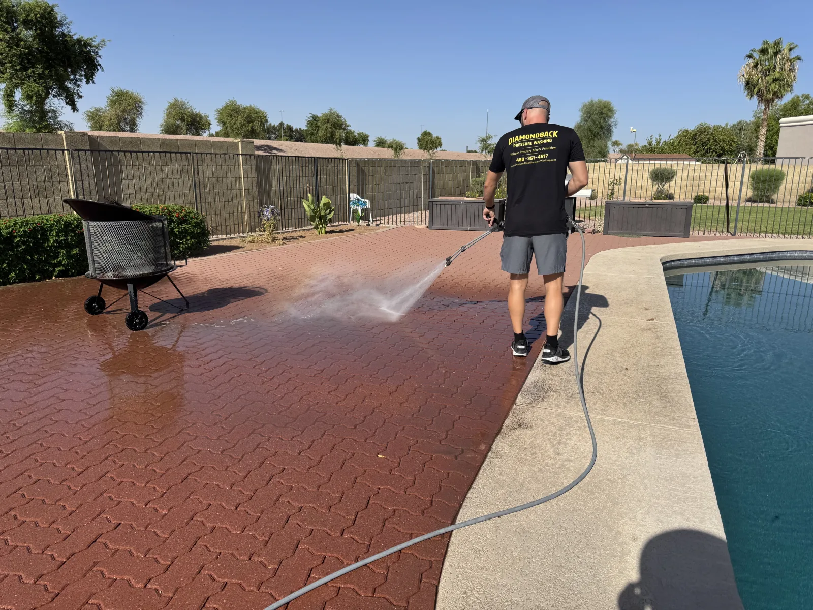 Diamondback technician pressure washing a paver pool deck in Gilbert, Arizona