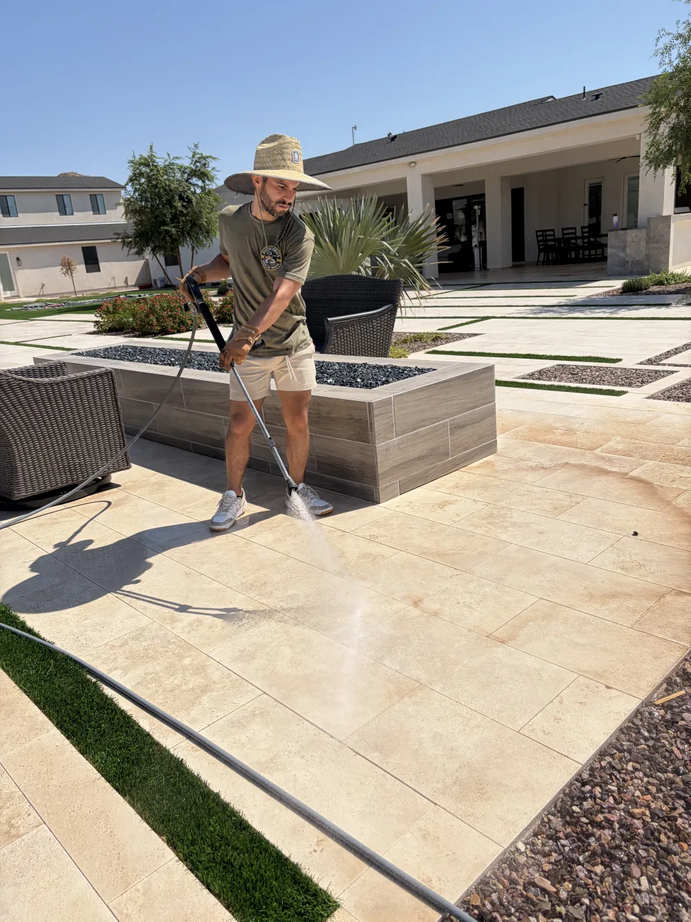 Technician cleaning a travertine courtyard in Arizona heat